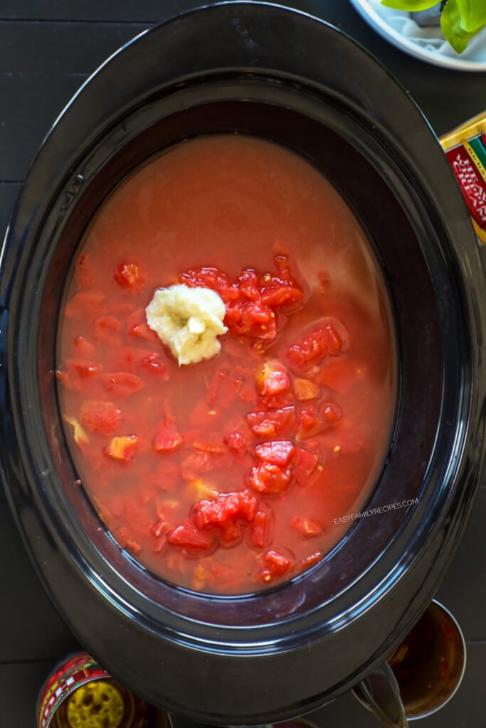 How to make tomato basil soup in a crockpot step 1: Add crushed tomatoes and garlic to the crockpot.