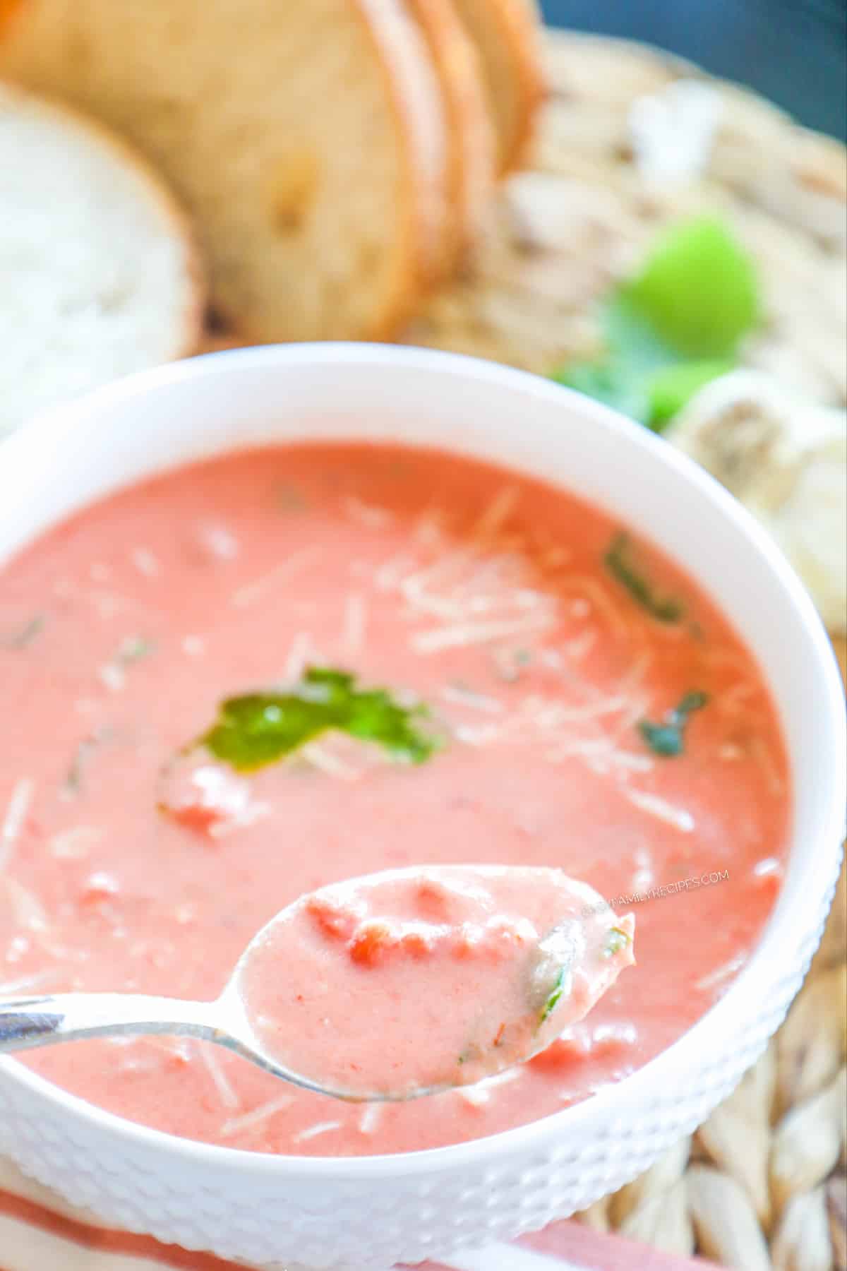 Tomato basil soup being eaten with a spoon.