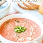 Slow cooker tomato basil soup prepared and served in a bowl with bread.