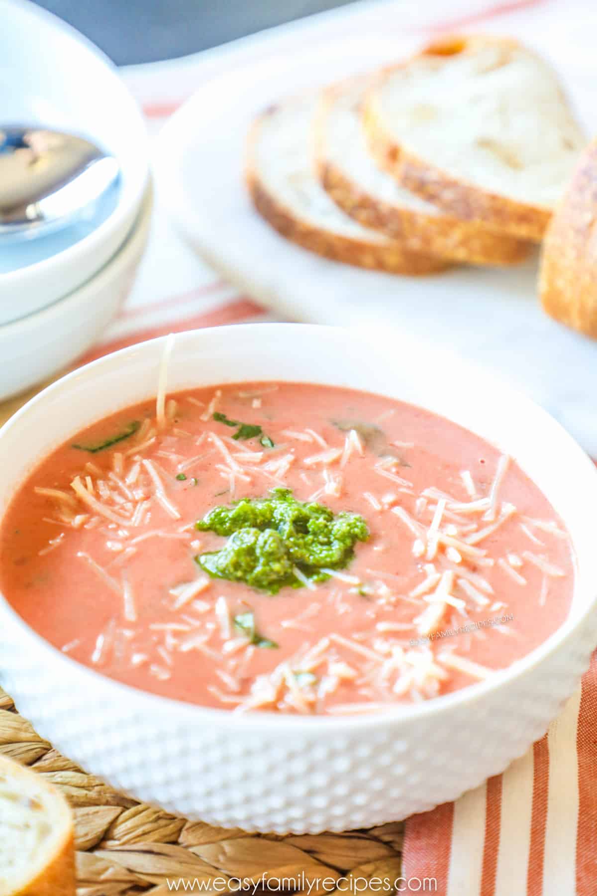 Creamy Tomato Soup in a bowl garnished with parmesan and pesto.