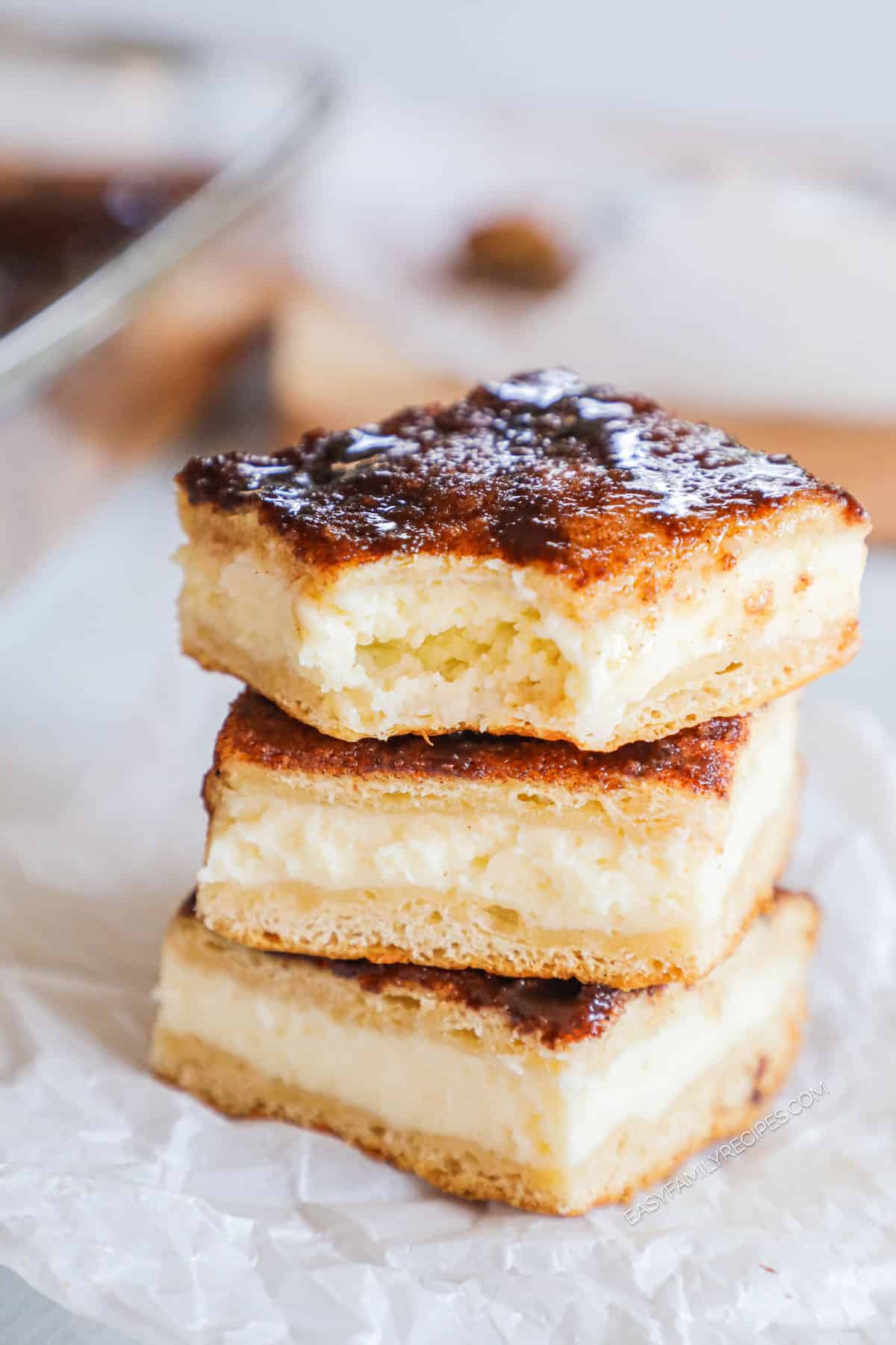 Three churro cheesecake bars stacked on top of each other with bite taken out of top bar