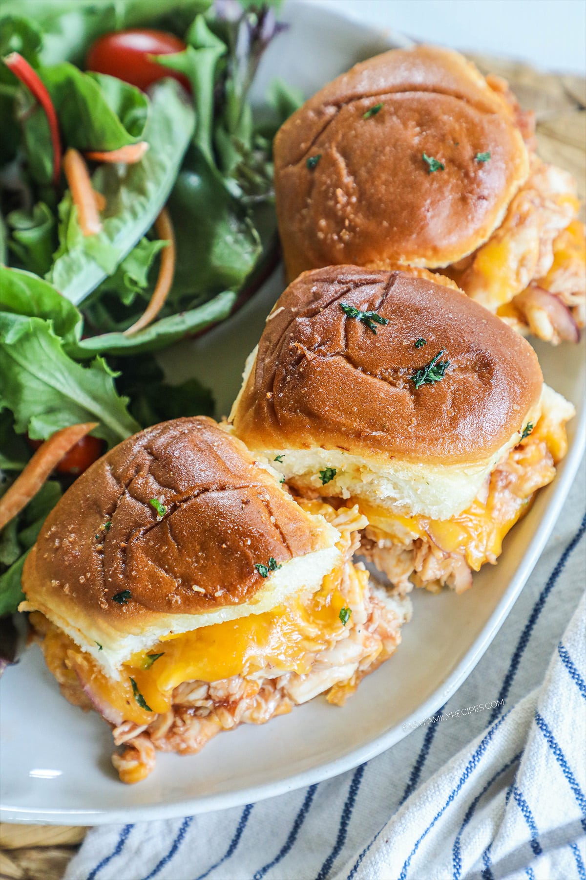 three bbq chicken sliders on hawaiian rolls on a plate.