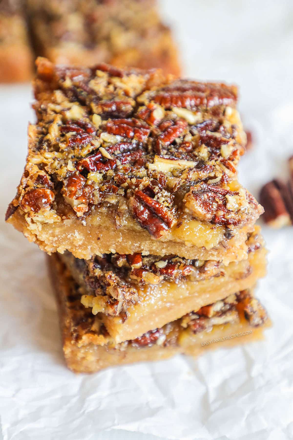 three gooey pecan pie bars stacked.