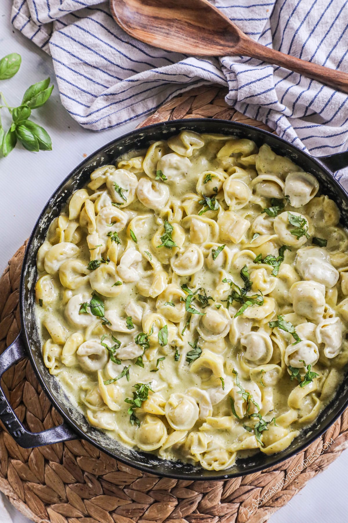 a large pan of creamy pesto sauce tossed with tortellini.