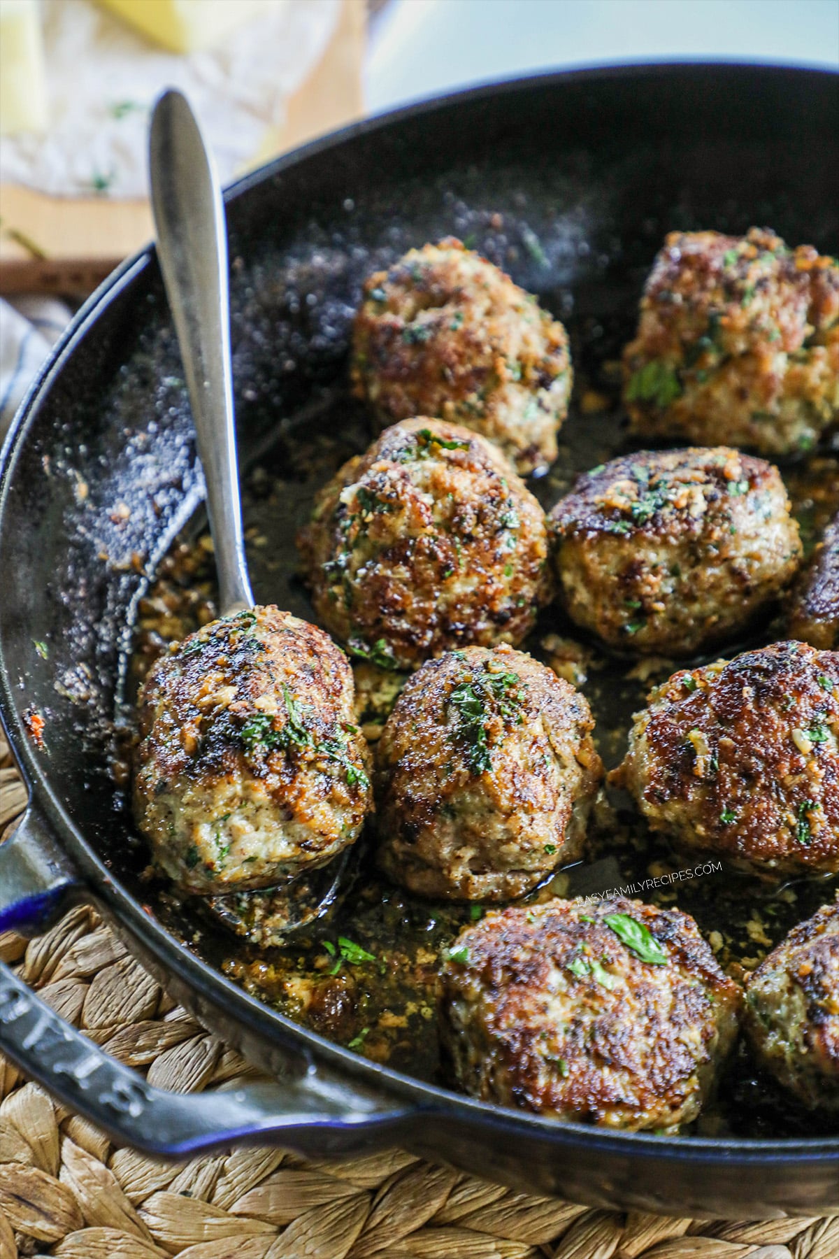 Ground Turkey Meatballs in garlic butter sauce being scooped out of a cast iron skillet.