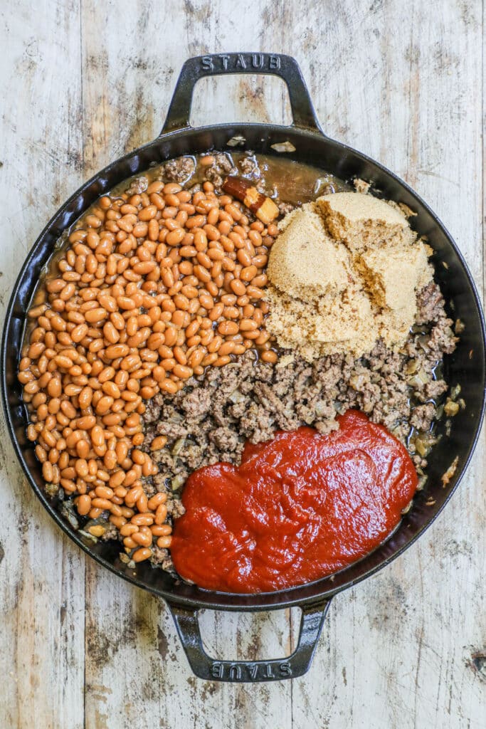 How to make Cowboy Baked Beans with ground beef Step 2: Add baked beans, brown sugar, chili sauce.