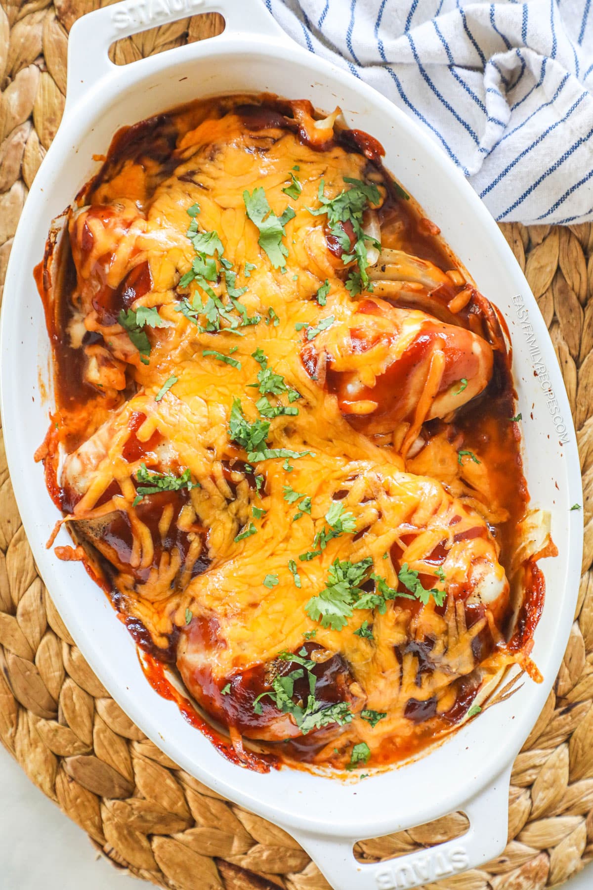 a white casserole dish full of chicken breasts baked with bbq sauce and shredded chedder cheese.