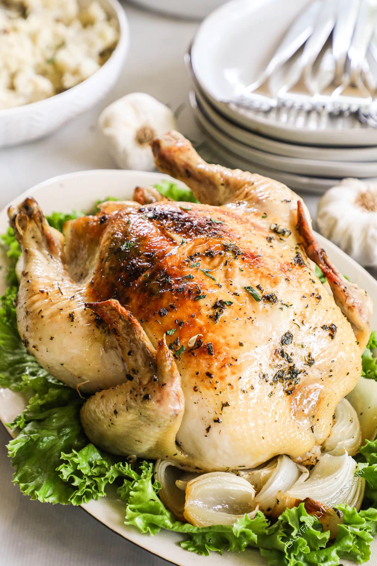 Whole Dutch oven roast chicken on platter with onions and lettuce