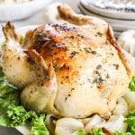 Whole Dutch oven roast chicken on platter with lettuce and onions