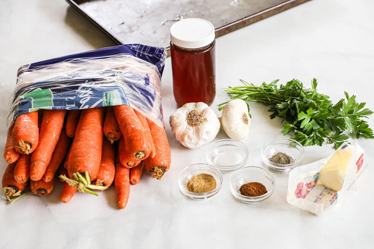 Ingredients for maple glazed carrots, including carrots, maple syrup, garlic, parsley, and spices