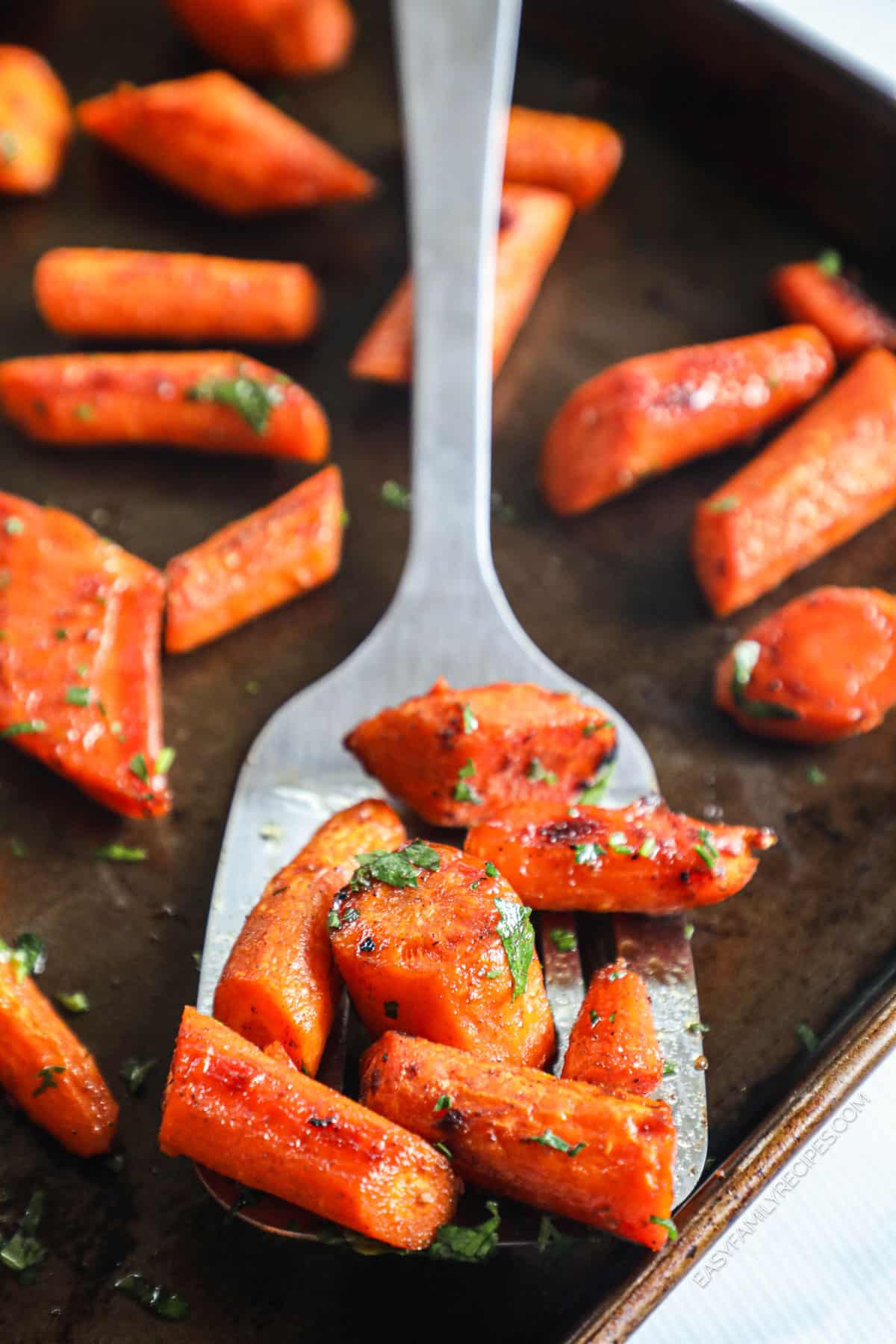 Roasted maple glazed carrots on spatula set on sheet pan