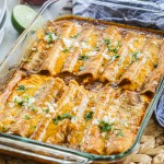 Tex Mex cheese enchiladas in a baking dish after baking to show melting cheese topping and garnish of chopped onions and cilantro.