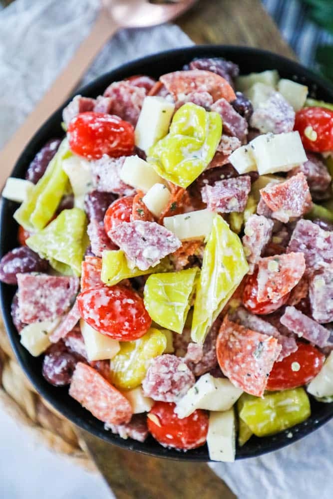 antipasto salad with pepperoncini's. tomatoes and salami in a black bowl