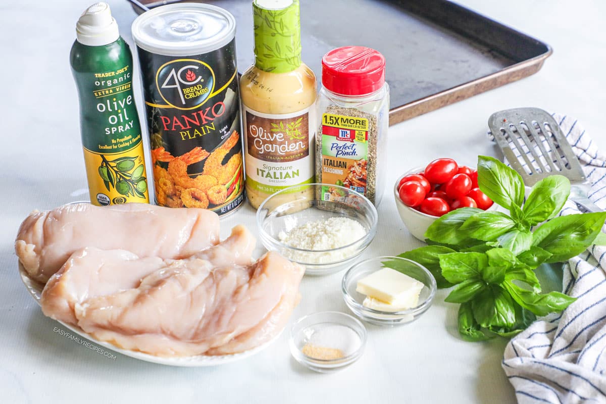 Ingredients for baked Italian chicken, including chicken breast, panko, Italian dressing, Italian seasoning, butter, Parmesan, tomatoes, and basil