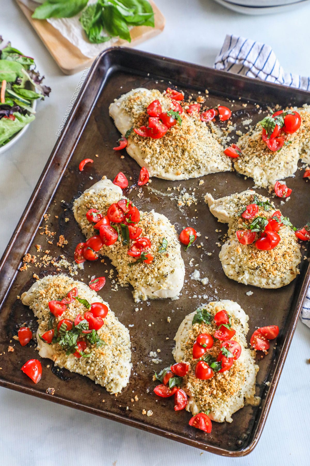 Sheet pan with baked Italian chicken topped with crispy panko, tomatoes, and basil