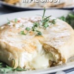 overhead of a wheel of baked brie in a golden pie crust topped with fresh herbs.