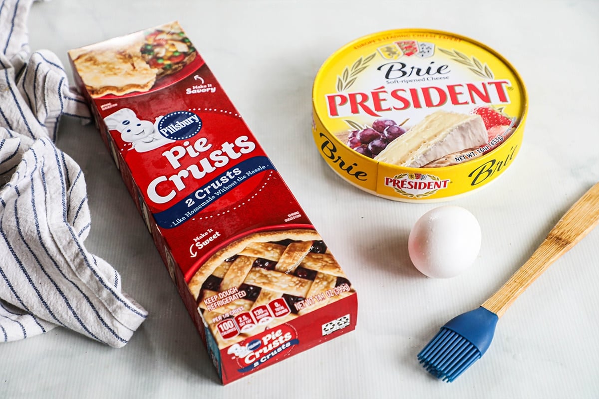 ingredients for baked brie - pie crust, brie cheese, eggs and a basting brush