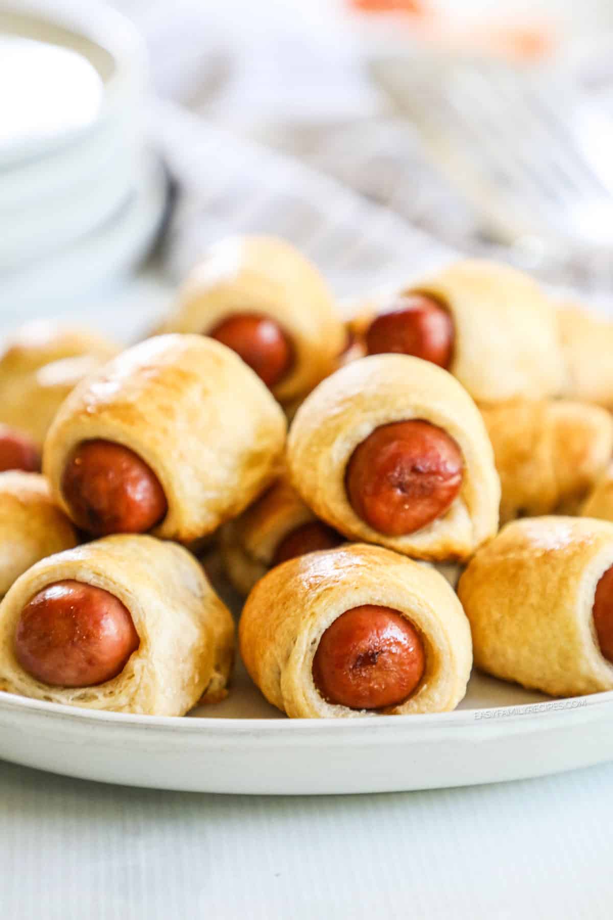 Stack of crescent roll pigs in a blanket on white plate