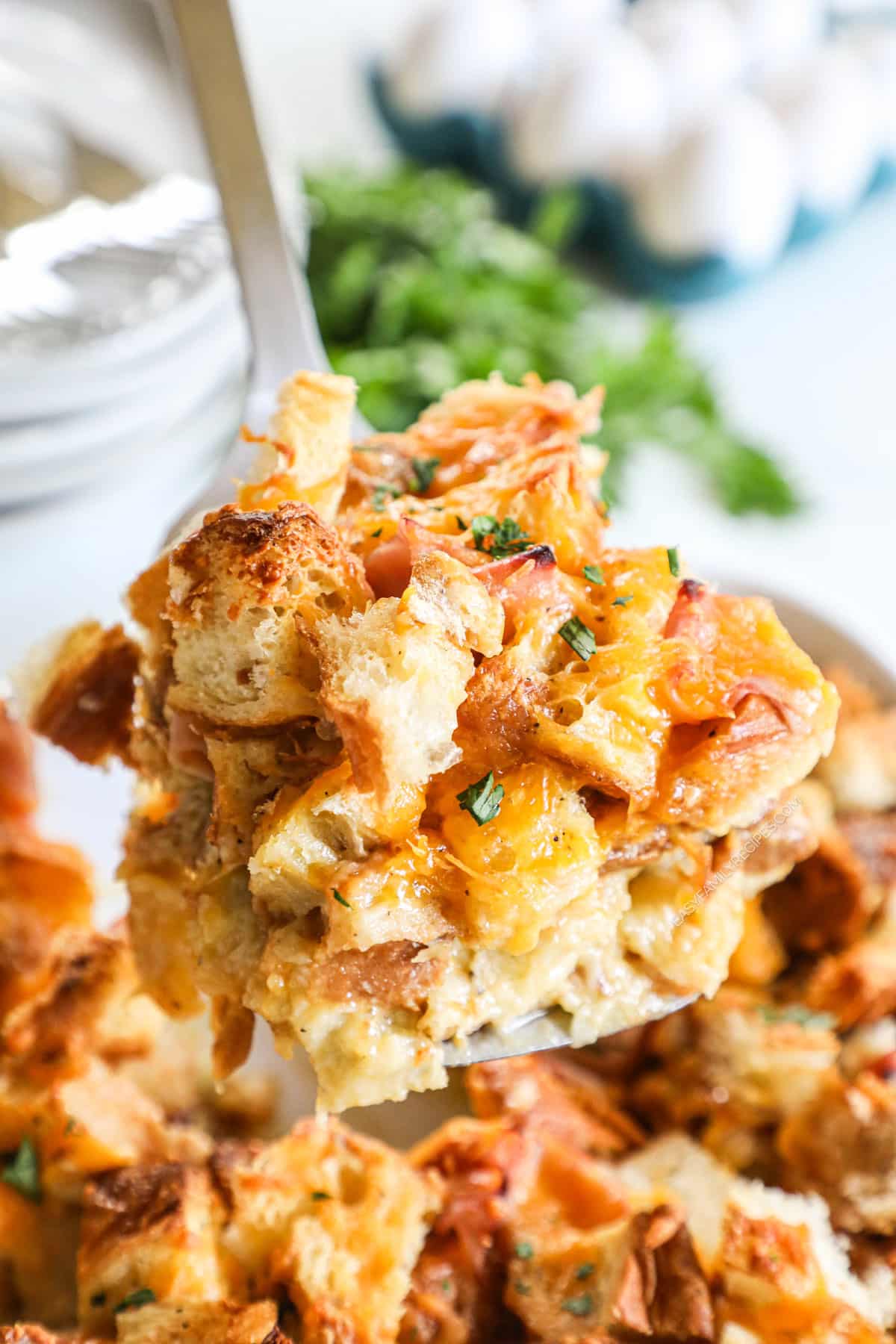 Spatula lifting serving of Ham & Cheese Croissant Breakfast Casserole from dish