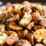 Herb Roasted Potatoes with crispy edges piled high on a baking sheet.