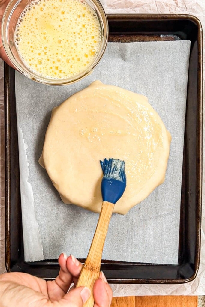 bake brie step 3 - crack 1 egg and spread all of the pie crust with your basting brush