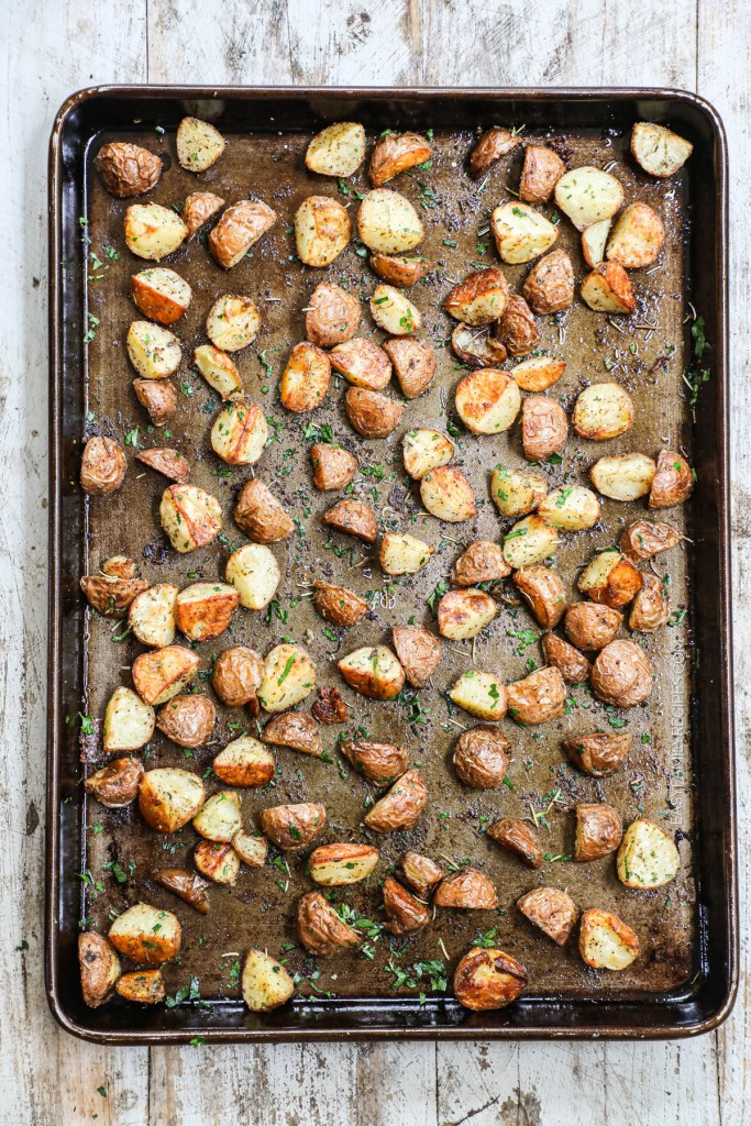 Step 4 of making herb roasted potatoes is baking the potatoes in the oven and tossing with fresh herbs once done