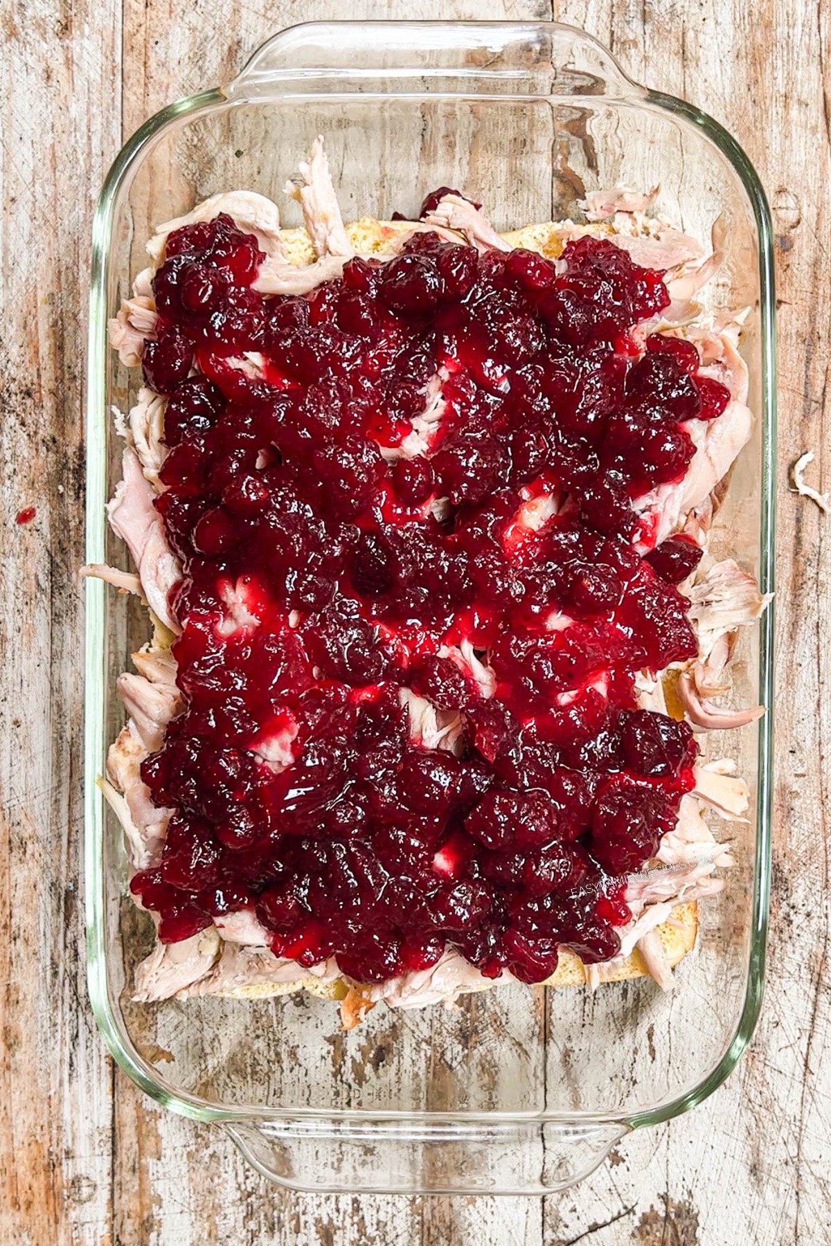 pan of shredded turkey topped with cranberry sauce