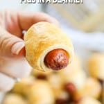 Hand holding crescent roll pig in a blanket