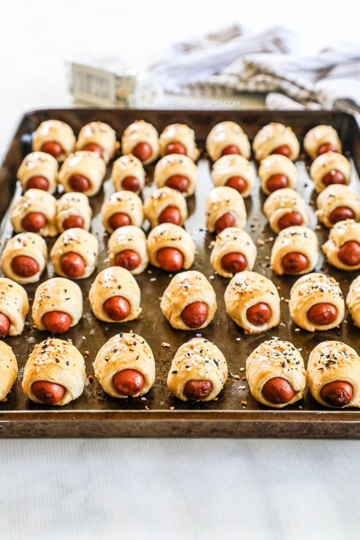 Mini pigs in a blanket lined up on a sheet pan