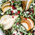 arugula pear pomegranate salad in a large salad bowl from above.