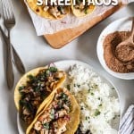 Two Mexican street chicken tacos on plate with rice and beans