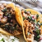 Two Mexican street chicken tacos on plate with rice