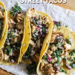 Mexican chicken street tacos lined up on parchment covered board