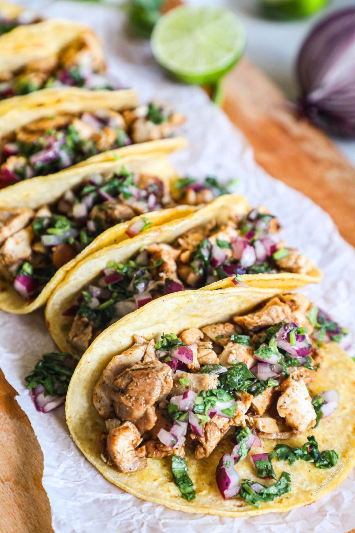 Mexican chicken street tacos lined up on parchment covered board