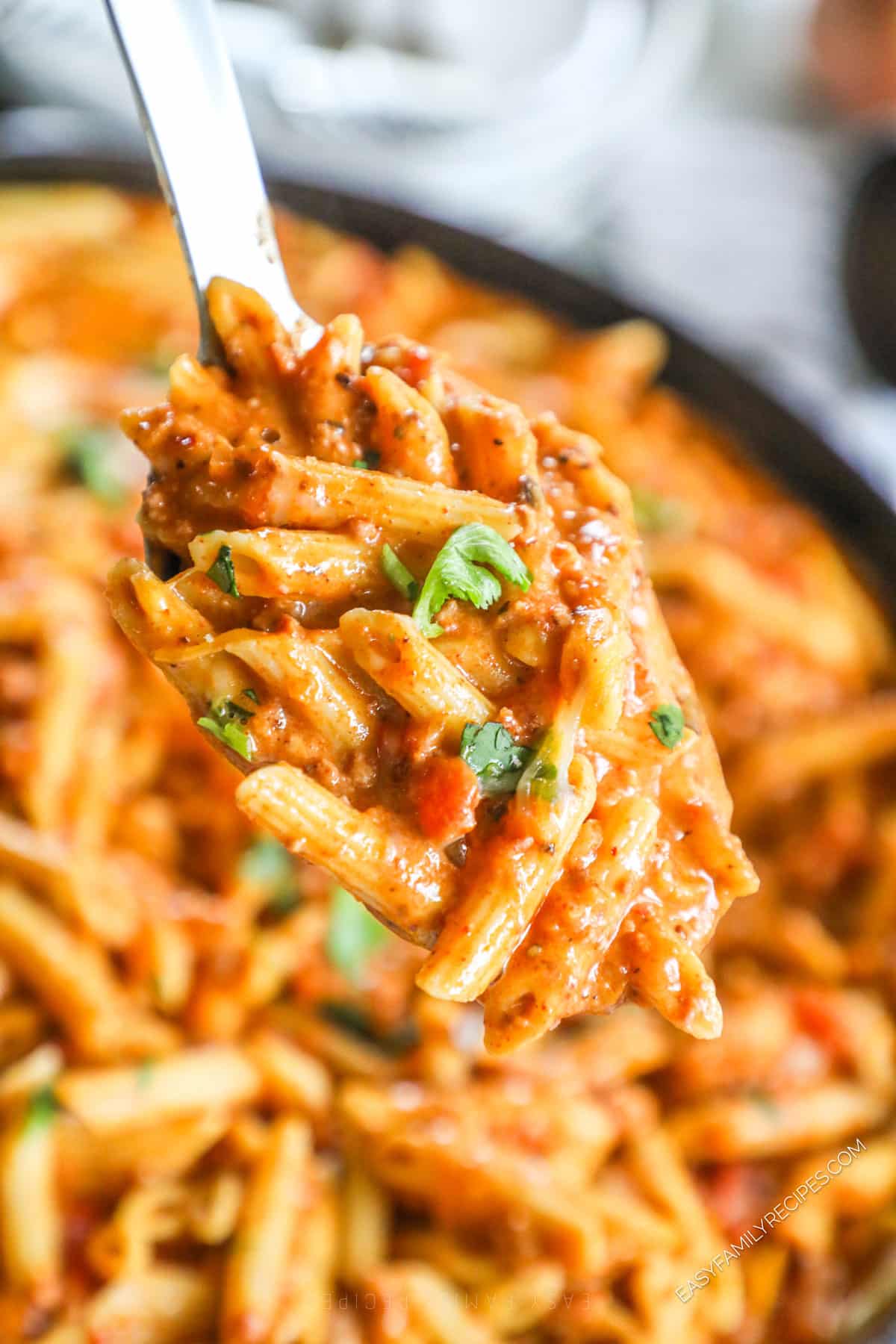 Spoonful of chorizo pasta held over pan