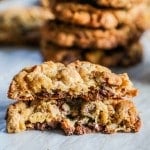 two halves of a cowboy cookie stacked with more cookies stacked in the background.