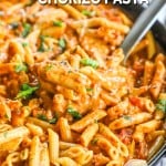 Serving spoon scooping creamy chorizo pasta from skillet