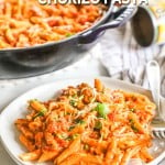 Plate of creamy pasta with chorizo with skillet of pasta in background