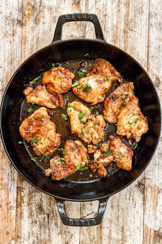 Overhead view of Mexican chicken thighs in skillet with cilantro garnish