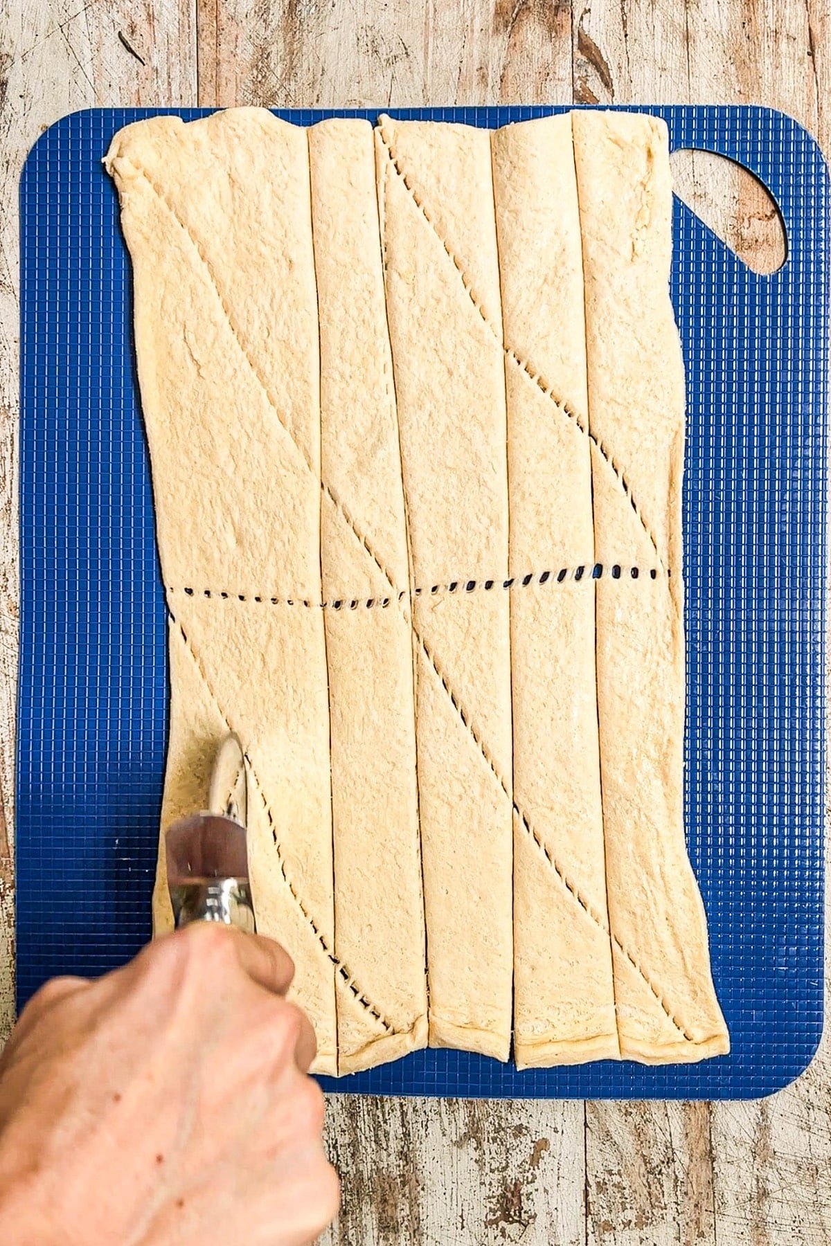 Using pizza cutter to cut crescent roll dough