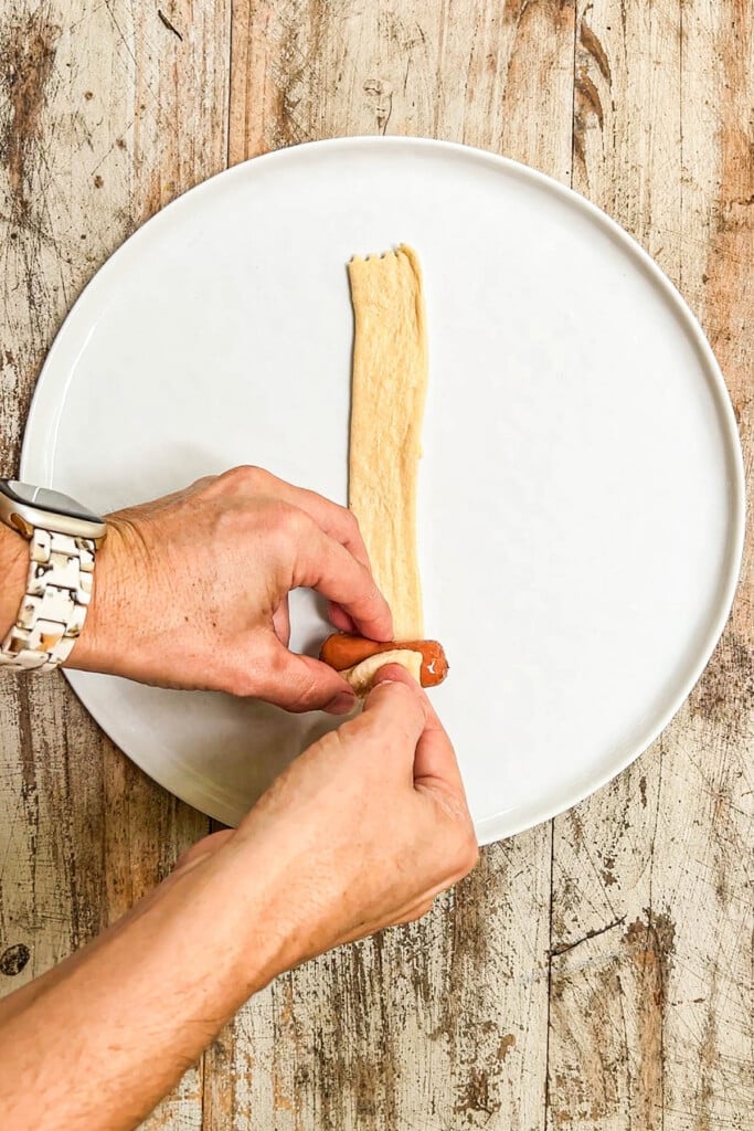 Rolling cocktail sausage in crescent roll dough