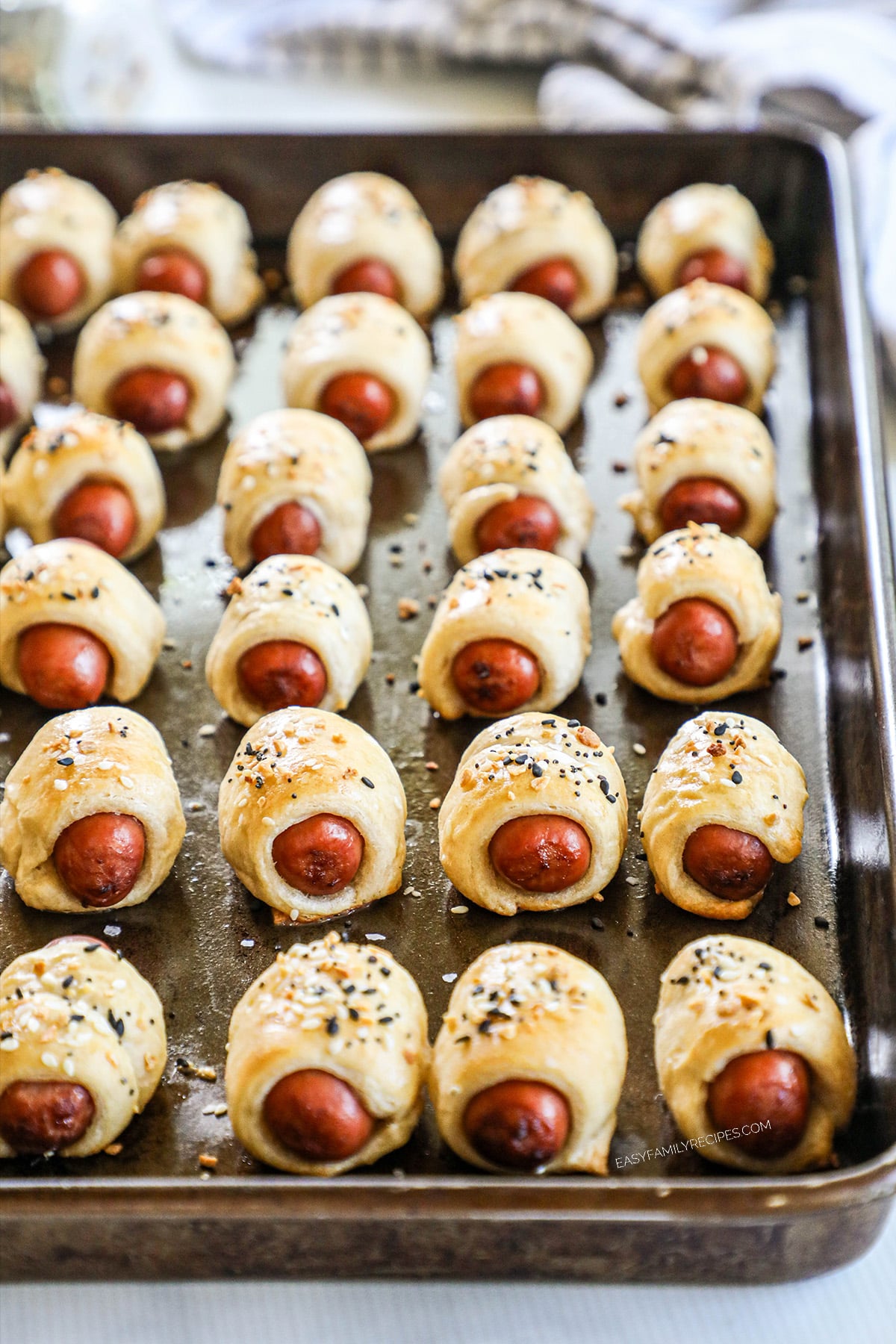 Mini pigs in a blanket lined up on a sheet pan