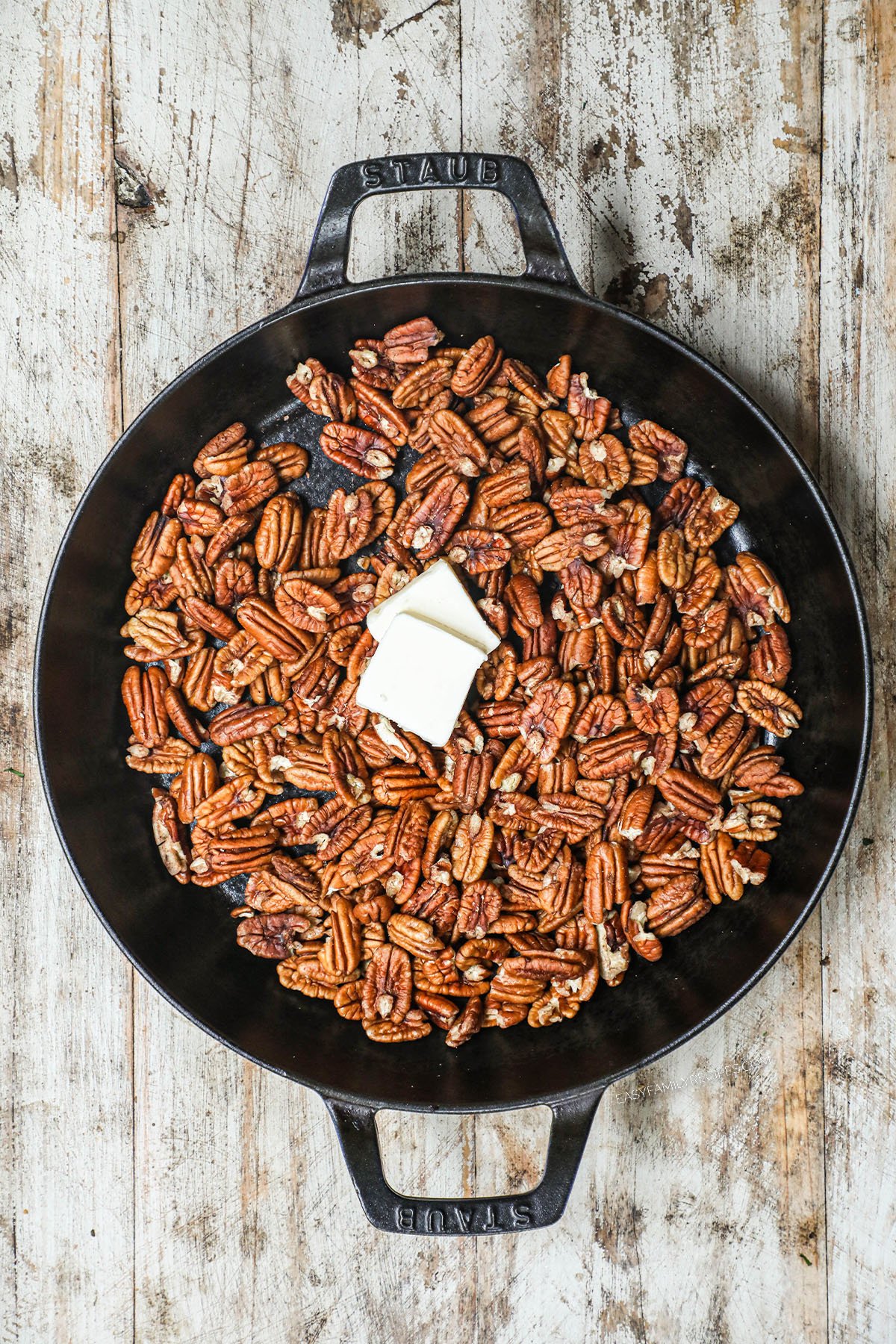 butter added to pecans in a skillet.