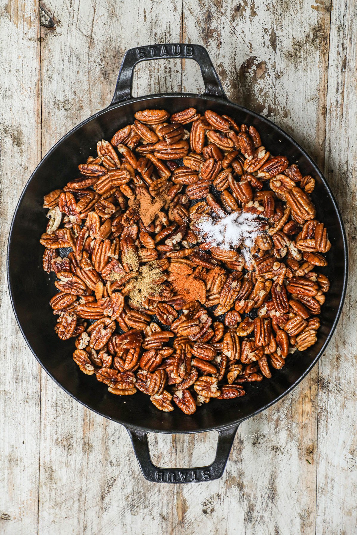 pecans in a skillet sprinkled with spices.