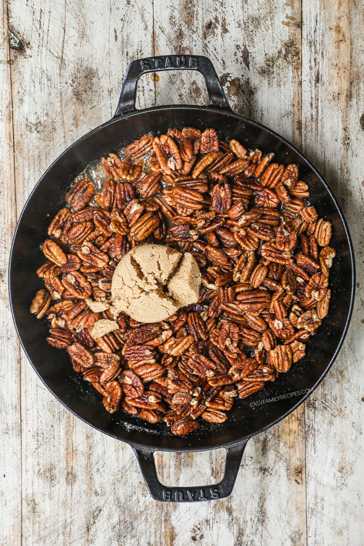 brown sugar added to pecans in a skillet.