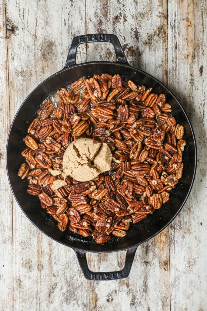 brown sugar added to pecans in a skillet.