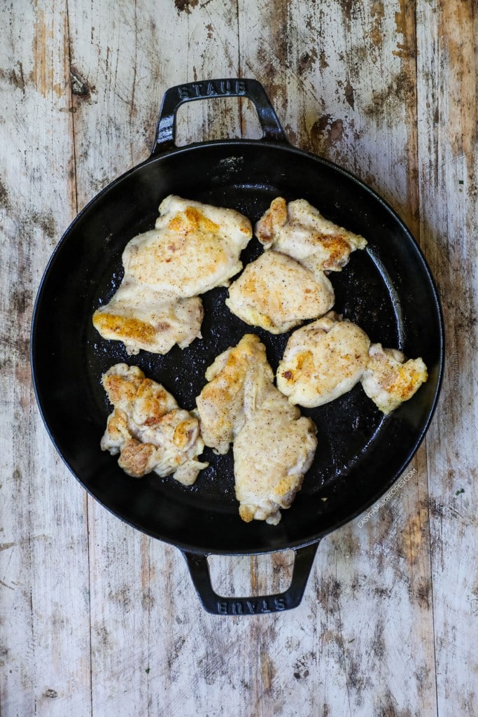 Overhead view of chicken thighs cooking in skillet