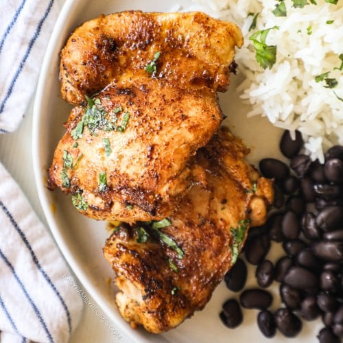 Closeup of Mexican chicken thighs on plate with rice and beans