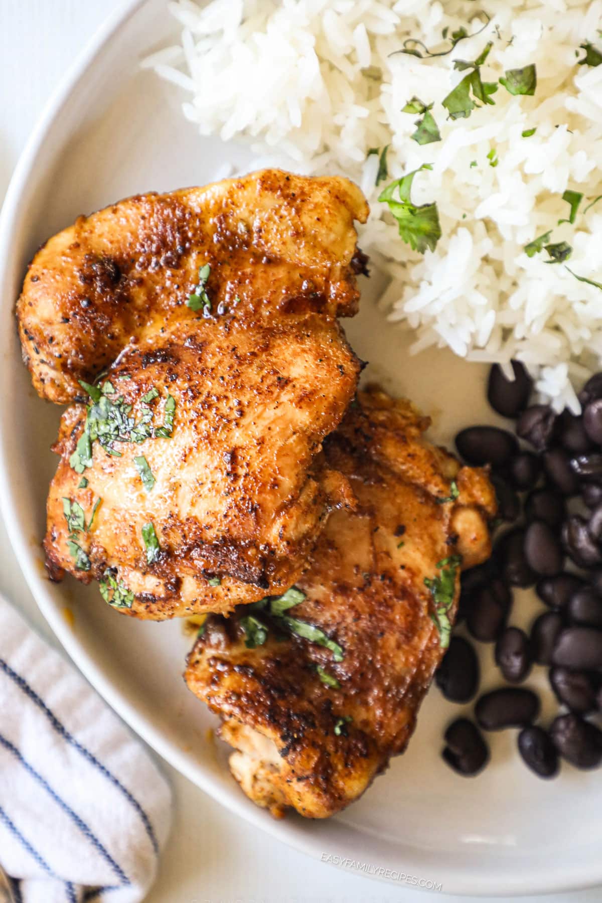 Overhead view of Mexican chicken thighs on plate with rice and beans