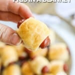 Hand holding crescent roll pig in a blanket